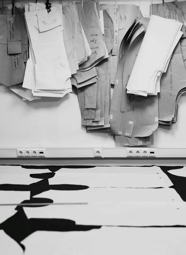 Paper patterns hanging above a cutting table in the Chula atelier