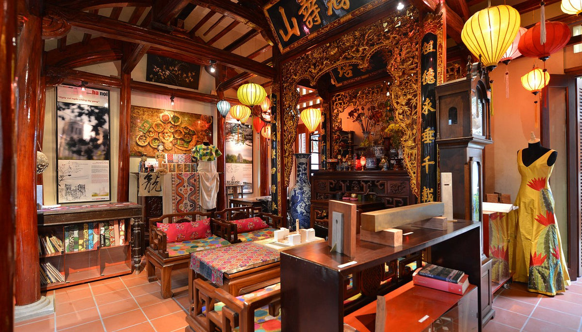 The Chula House interior: carved red timber, silk lanterns and a dress form in a painted gown
