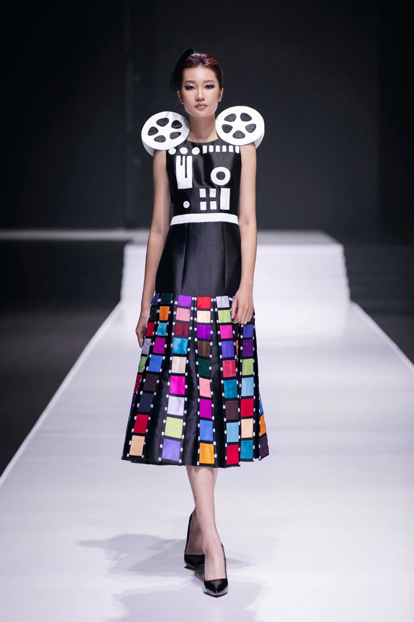 Model on the runway in a dress painted with film reels above a skirt of frames
