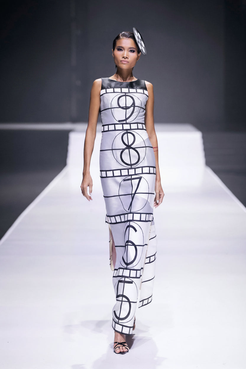 Model on the runway in a white gown printed with a film countdown