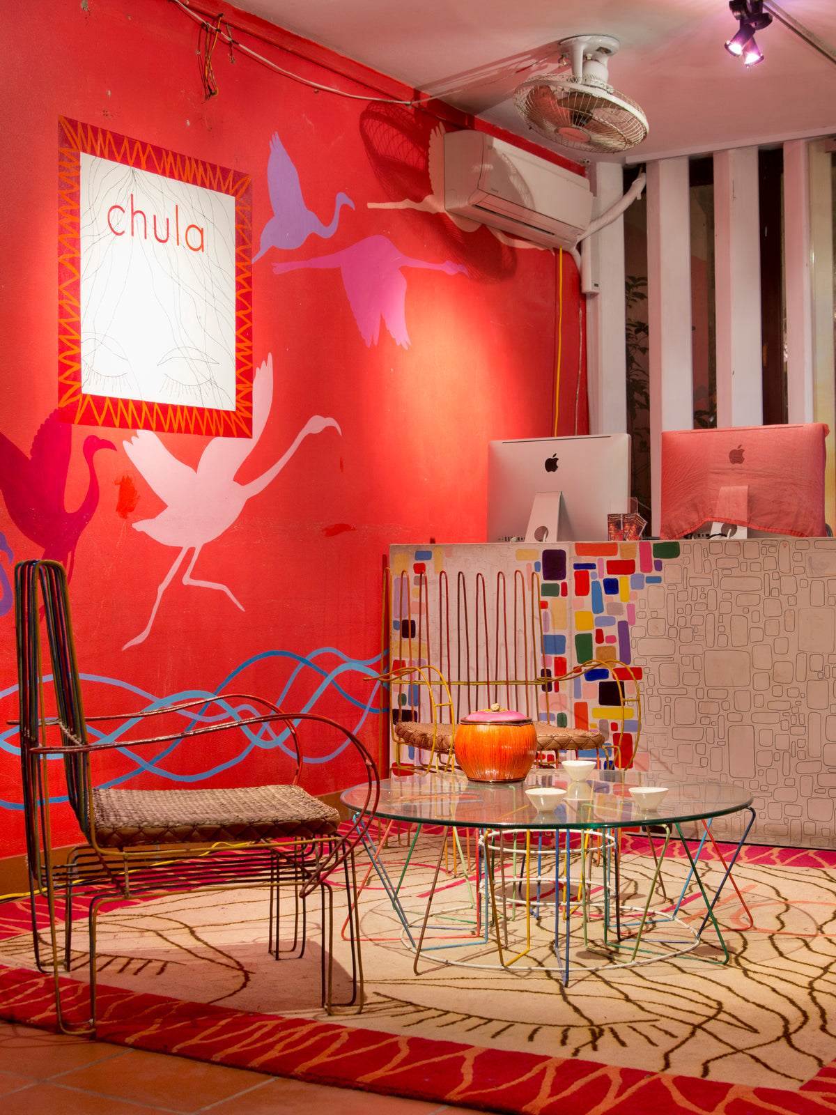 The Chula studio, painted red with flamingos, desks and patchwork stools