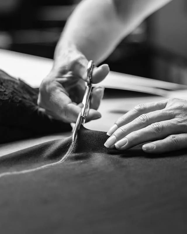 Hands guiding shears through cloth in the Chula atelier